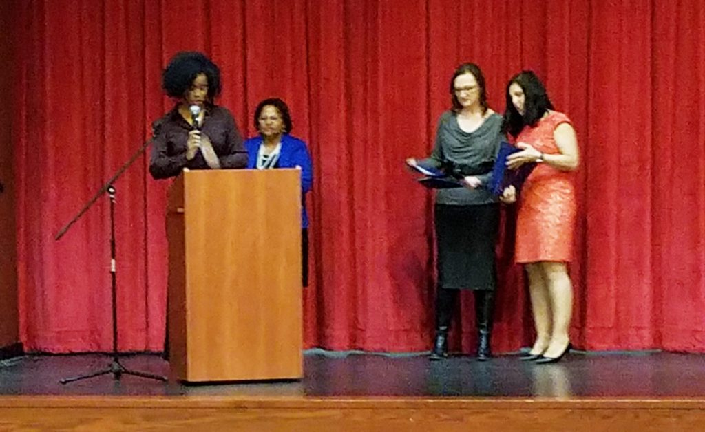 The Essex County School Boards Association gathered at Liberty Middle School in West Orange to honor 30 student “unsung heroes.” Pictured (l-r) are Essex County School Boards Association President Sandra Mordecai, at the podium; Jennifer Woodhouse, association vice president; and Judith Amorim Dias, vice president. To the right is a Montclair School District official. 
